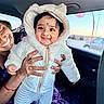 baby, child, smiling, adult, hand, car_interior, window, sunset, jacket, hood, bear_ears, striped_pants, happy, person, clothing, portrait, seated, fun, cute, warm