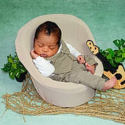 Noah a rejoint le concours — aidez-le/la à gagner de superbes lots ! baby, sleeping, chair, beige, outfit, toy_guitar, plants, green_background, rope_mat, cozy, nursery, cute, peaceful, infant, portrait, relaxed, indoor, child, small, decor