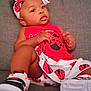 baby, infant, child, red_clothing, headband, ladybug_pattern, sneakers, couch, indoor, portrait, cute, fashion, footwear, accessory, skin, face, hands, seated, expression, home
