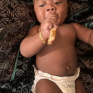 King joined the competition — help win amazing prizes! baby, diaper, bracelet, snack, lying_down, person, skin, hand, face, mouth, food, blanket, pattern, comfort, infant, cute, indoors, young_child, resting, casual