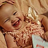 Lilly-Ann is registered to the contest to win money with this photo: baby, infant, child, smiling, laughing, portrait, close_up, face, eyes, mouth, tongue, bed, blanket, bedroom, indoor, cozy, dress, bottle, sitting, happy