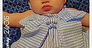 Lilly-Ann is registered to the contest to win money with this photo: baby, infant, child, portrait, lying_down, headband, bow, striped_clothing, dress, cushion, blanket, bed, indoors, face, eyes, lips, arms, legs, patterned_background, text_overlay