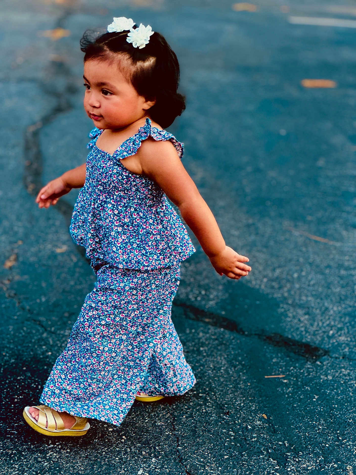 Abigail joined the competition — help win amazing prizes! toddler, child, girl, outdoor, walking, blue_flower_clothing, sandals, hair_accessory, curly_hair, pavement, side_view, cute, fashion, summer, casual, portrait, young_child, expression, natural_light, playful