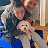 clothing, device, dog, face, floor, furniture, hair, happy, home, human, indoor, man, person, pet, smiling, technology, together, wheelchair, woman, wood_floor
