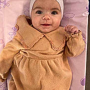 Malya participe au concours pour gagner de l'argent avec cette photo : baby, infant, smiling, face, eyes, hat, cap, dress, knitwear, peach_color, pink_background, blanket, lying_down, portrait, newborn, cute, rosy_cheeks, hand, gaze, pattern