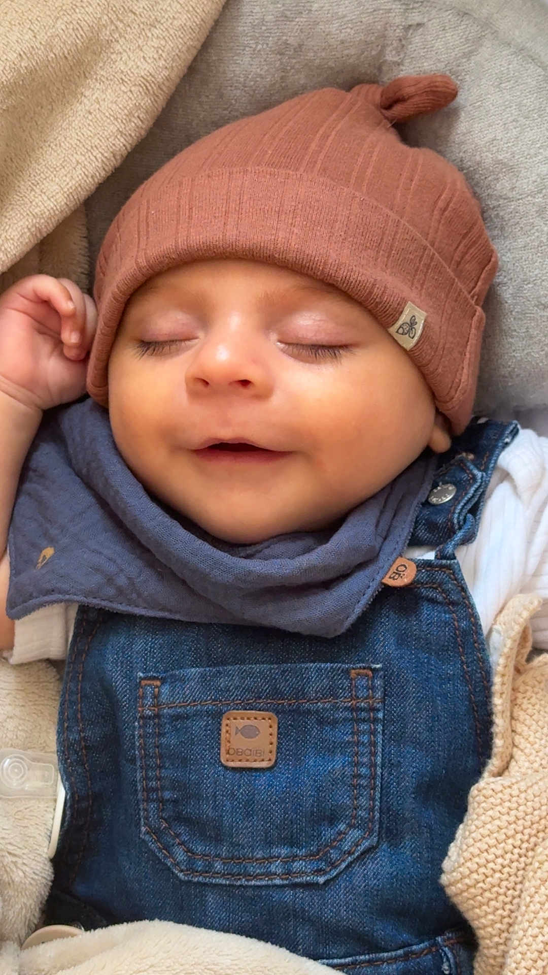 Swann participe au concours pour gagner de l'argent avec cette photo : baby, sleeping, hat, denim_overalls, blanket, cozy, child, smile, cute, infant, knit_hat, clothing, texture, face, peaceful, resting, young_child, soft, portrait, comfort