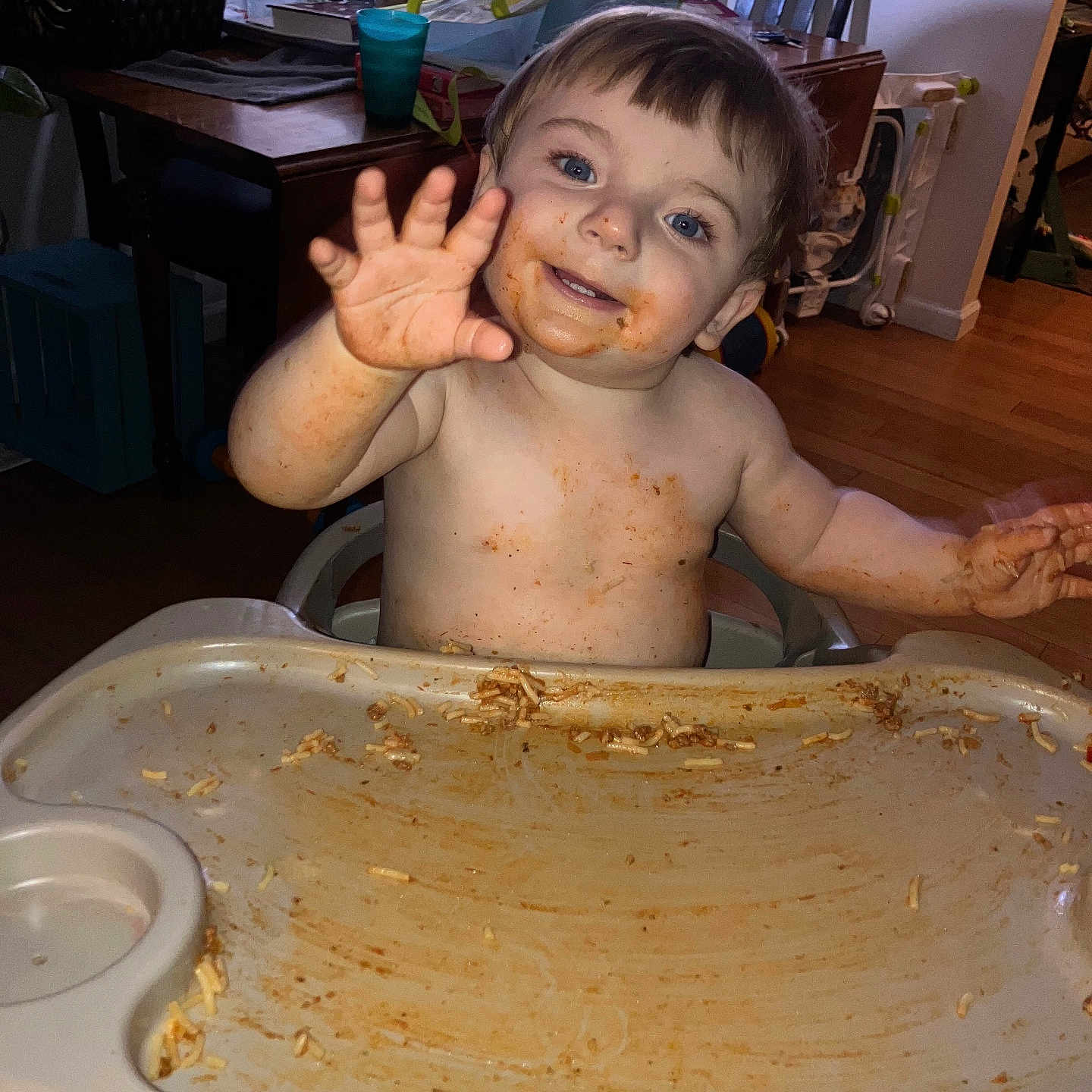 Jonah is registered to the contest to win money with this photo: toddler, child, messy, high_chair, spaghetti, food, face, blue_eyes, indoor, dining_room, wood_floor, table, chair, globe, person, smiling, hand, hair, plate, baby