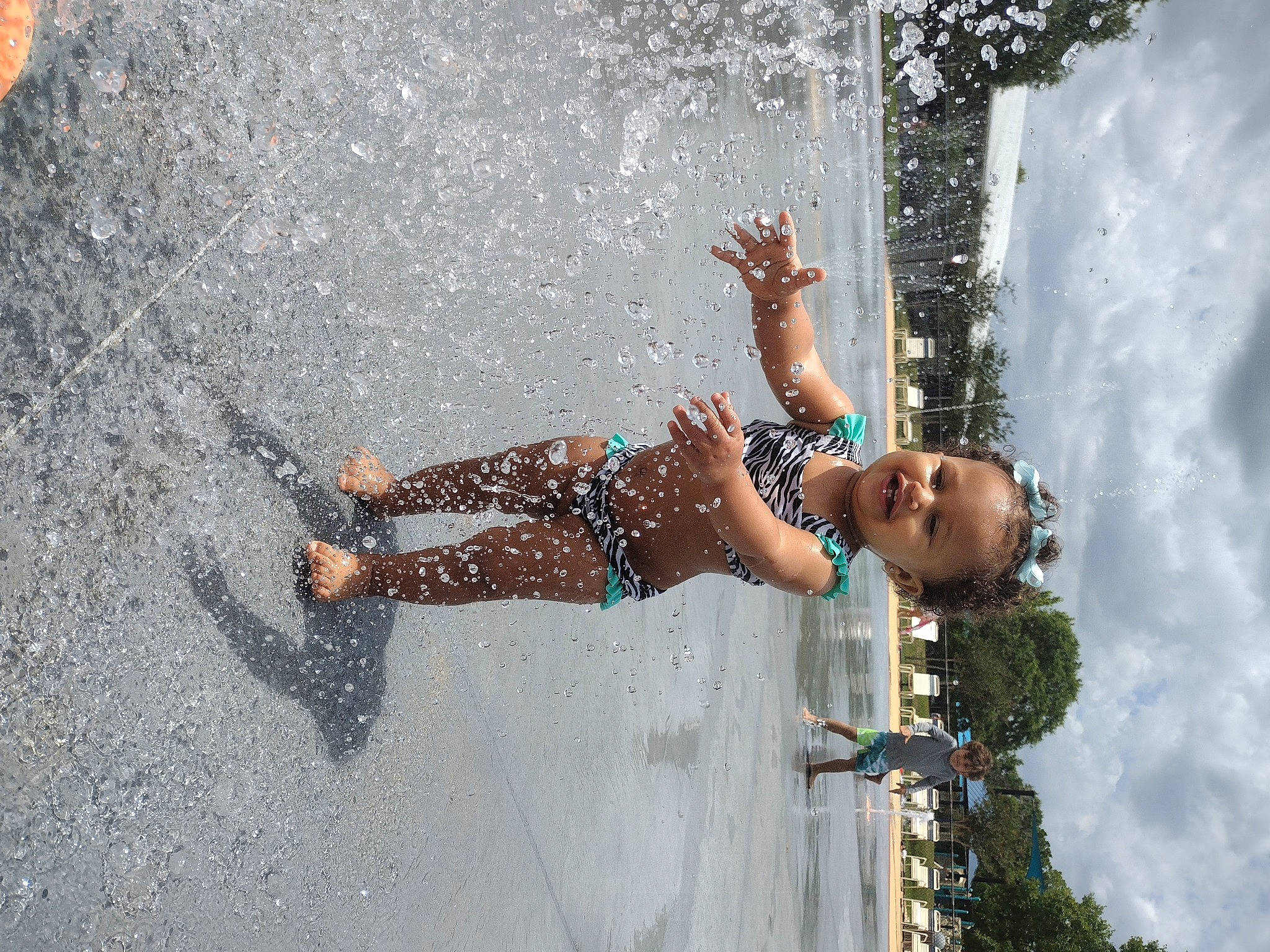 Rihanna is registered to the contest to win money with this photo: arm, asphalt, barefoot, child, concrete, dress, foot, fun, happy, human_leg, leisure, people_in_nature, person, recreation, street_fashion, thigh, toddler, tree, waist, water