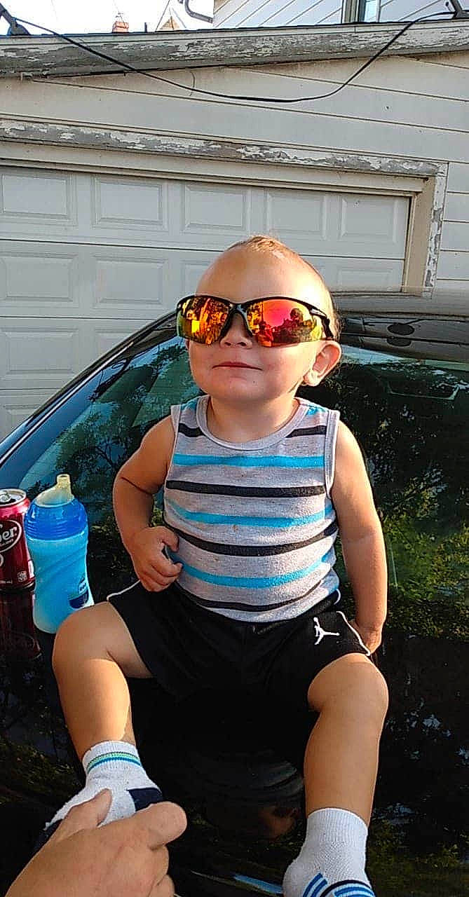 Elijah Morris is registered to the contest to win money with this photo: automotive_exterior, automotive_lighting, baby, baby_toddler_clothing, bumper, child, electric_blue, eyewear, fun, goggles, headgear, hood, leisure, person, personal_protective_equipment, recreation, shorts, sleeve, sunglasses, toddler