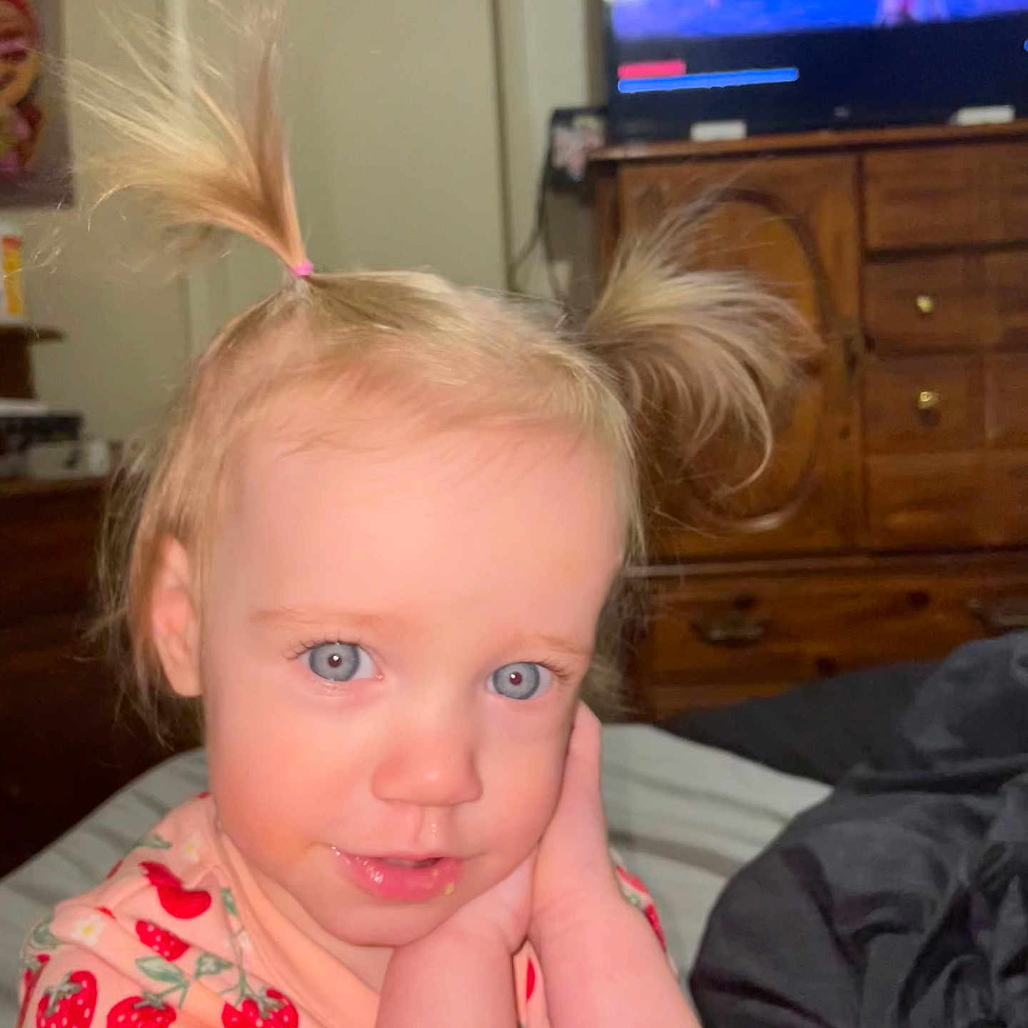 Ayrabella joined the competition — help win amazing prizes! bed, bedroom, blanket, blonde_hair, blue_eyes, child, cute, dresser, furniture, hands_on_face, indoor, person, pigtails, pink_clothing, portrait, smiling, soft_lighting, strawberry_pattern, television, toddler