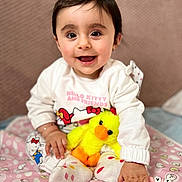 Natalia is registered to the contest to win money with this photo: baby, child, smiling, happy, plush_toy, yellow_duck, hello_kitty, clothing, socks, blanket, indoor, cute, portrait, person, toy, pink, pattern, hand, face, hairclip