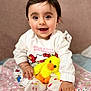 baby, child, smiling, happy, plush_toy, yellow_duck, hello_kitty, clothing, socks, blanket, indoor, cute, portrait, person, toy, pink, pattern, hand, face, hairclip
