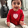baby, child, smiling, red_dress, heart, sitting, carpet, indoors, cute, happy, face, person, young_child, long_sleeve, white_tights, footwear, portrait, front_view, small_person, bright