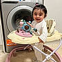 Natalia joined the competition — help win amazing prizes! baby, baby_walker, smiling, happy, indoor, washing_machine, kitchen, floor, toy, white_clothing, footwear, playful, child, young_child, walker, home, appliance, cute, standing, infant