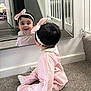 baby, child, mirror, reflection, pink_clothing, headband, bow, carpet, indoor, smiling, cute, sitting, person, hair, face, home, stairs, railing, door, floor