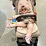 baby, baby_shoes, blanket, casual, child, comfort, cute, expression, floor, footwear, headband, indoor, infant, pacifier, person, pink_clothing, playful, seated, stroller, toy