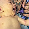 baby, infant, tattoo, hand, smile, laughing, skin, blanket, person, closeup, cute, happy, human, fingers, naked_torso, baby_skin, touch, care, warmth, intimate