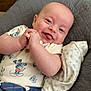 baby, infant, smiling, tongue_out, mickey_mouse, clothing, quilted_cushion, blanket, blue_shorts, cute, happy, child, face, skin, indoor, portrait, resting, relaxed, person, newborn
