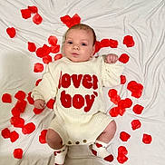Lincoln joined the competition — help win amazing prizes! adorable, baby, child, cute, face, hands, heart_pattern, indoor, infant, knitted_outfit, lover_boy, lying_down, portrait, red_petals, red_text, rose_petals, socks, white_clothing, white_sheet, young_baby