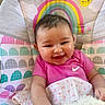 Patsyn is registered to the contest to win money with this photo: baby, blanket, child, close_up, clouds, face, happy, high_chair, indoor, infant, patterned_background, photography, pink_shirt, plush_toy, portrait, rainbow, sitting, smiling, sun, toy