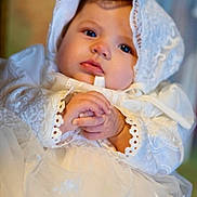 Scarlett Hopkins is registered to the contest to win money with this photo: baby, infant, lace, white_dress, bonnet, hands, clasped_hands, portrait, closeup, soft_lighting, cute, child, face, young, indoors, serene, adorable, clothing, expression, newborn