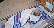 David joined the competition — help win amazing prizes! newborn, baby, hospital, bassinet, blanket, pacifier, medical_equipment, floor, wooden_cabinet, person, infant, wrapped, bed, indoors, patient, cute, peaceful, hospital_room, healthcare, sleeping