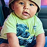 baby, child, cap, backwards_cap, green_tshirt, monster_truck_graphic, sitting, curious_expression, indoors, closeup, cute, chubby, hand, foot, skin, portrait, infant, casual_clothing, young_child, person