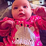 baby, child, infant, portrait, pink_outfit, giraffe_onesie, onesie, smiling, wide_eyes, sitting, indoor, living_room, chair, couch, window, television, coffee_table, bright_clothing, text_overlay, monday