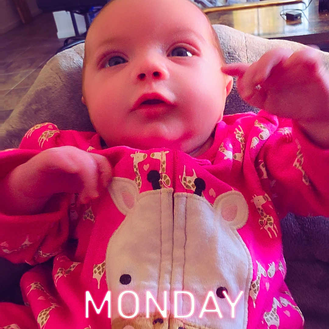 Paisley joined the competition — help win amazing prizes! baby, child, infant, portrait, pink_outfit, giraffe_onesie, onesie, smiling, wide_eyes, sitting, indoor, living_room, chair, couch, window, television, coffee_table, bright_clothing, text_overlay, monday
