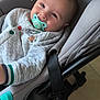baby, pacifier, car_seat, gray, quilted_jacket, buttons, smiling, face, child, indoor, safety_warning, airbag, infant, cute, happy, seated, clothing, closeup, head, person