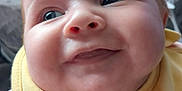 Dolly-Mae is registered to the contest to win money with this photo: baby, close_up, smiling, yellow_bib, chubby_cheeks, indoor, cute, face, child, apparel, infant, person, young_child, portrait, happy, looking_away, soft_lighting, cozy, clothing, expression