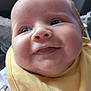 baby, close_up, smiling, yellow_bib, chubby_cheeks, indoor, cute, face, child, apparel, infant, person, young_child, portrait, happy, looking_away, soft_lighting, cozy, clothing, expression