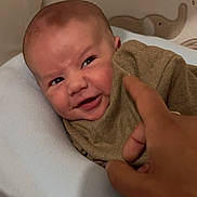 Eden a rejoint le concours — aidez-le/la à gagner de superbes lots ! baby, infant, face, smile, blanket, hand, finger, brown_clothing, cozy, indoor, soft_lighting, head, skin, person, expression, cute, child, playful, portrait, decor