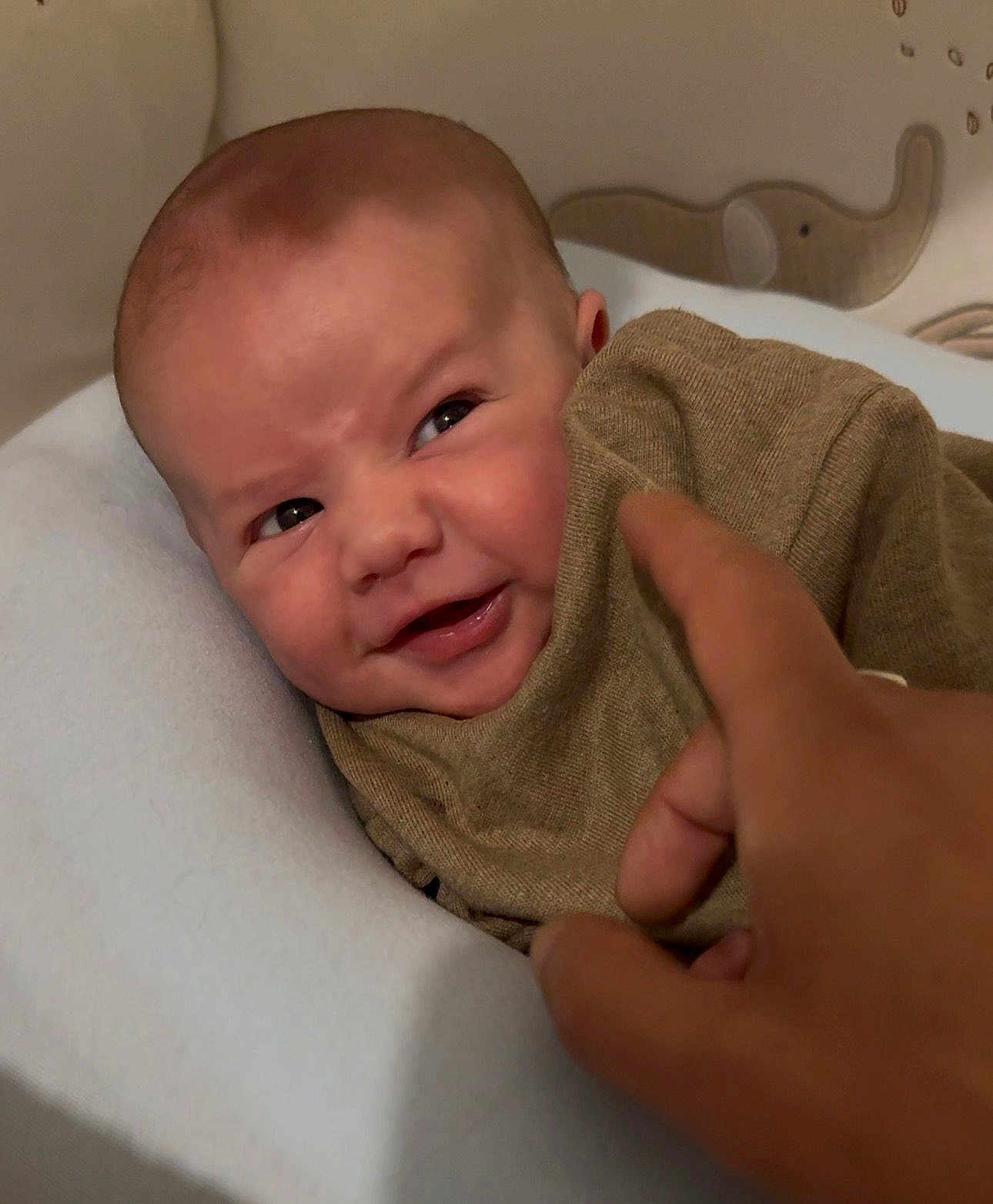Eden a rejoint le concours — aidez-le/la à gagner de superbes lots ! baby, infant, face, smile, blanket, hand, finger, brown_clothing, cozy, indoor, soft_lighting, head, skin, person, expression, cute, child, playful, portrait, decor