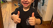 Néo a rejoint le concours — aidez-le/la à gagner de superbes lots ! child, smiling, thumbs_up, black_tshirt, indoor, wooden_floor, clothing, laundry_rack, paper_bag, happy, short_hair, person, home, casual, socks, furniture, doorway, backpack, young_child, portrait
