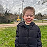 Néo a rejoint le concours — aidez-le/la à gagner de superbes lots ! child, boy, smiling, outdoor, grass, jacket, puffer_jacket, spiky_hair, cloudy_sky, trees, construction_equipment, lamp_post, fence, happy, portrait, casual_clothing, nature, young, person, daylight
