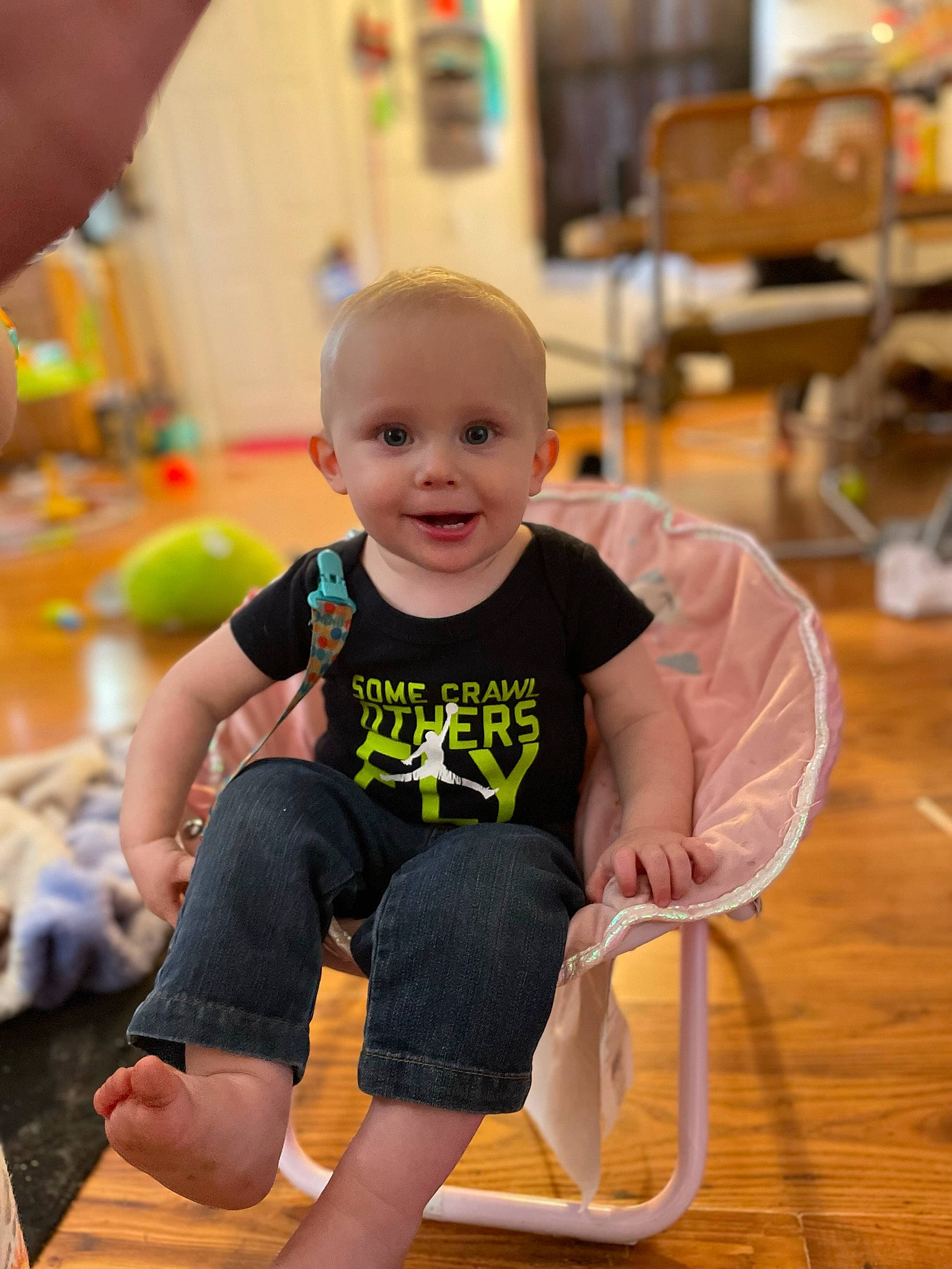 Ambrose is registered to the contest to win money with this photo: baby, baby_toddler_clothing, chair, child, event, flooring, fun, happy, human_leg, joy, knee, leisure, person, sitting, sleeve, smile, sportswear, t_shirt, television, thigh