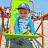 toddler, child, beach, sand, sunny, swimsuit, hat, chair, green, orange, ocean, summer, playful, outdoor, vacation, sunlight, people, tent, blue_sky, happy