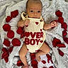 baby, infant, romper, red_hearts, lover_boy, rose_petals, blanket, soft_texture, lying_down, cute, curious, indoors, fabric, skin, newborn, small_hands, small_feet, red, cream, person