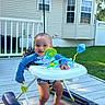 baby, walker, toy, outdoor, deck, grass, house, window, smile, happy, child, blue_clothing, sunlight, foot, person, play, summer, baby_boy, plastic, home