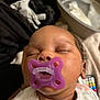 Asani is registered to the contest to win money with this photo: baby, sleeping, pacifier, purple_pacifier, infant, close_up, face, peaceful, cozy, blanket, clothing, indoors, newborn, child, person, soft_lighting, resting, cute, head, mouth