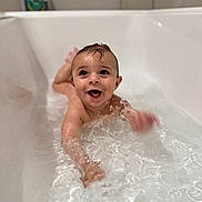 Kenai is registered to the contest to win money with this photo: baby, bathtub, water, splashing, wet_hair, joyful, child, smiling, bathroom, sitting, skin, head, face, playful, cute, indoor, young_child, happy, motion_blur, splash