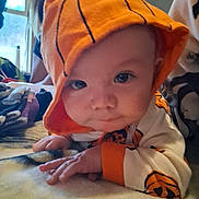 Joseph joined the competition — help win amazing prizes! baby, infant, child, hoodie, orange, pumpkin, blanket, face, eyes, hand, indoor, soft, cute, apparel, costume, portrait, lying_down, person, cozy, curious