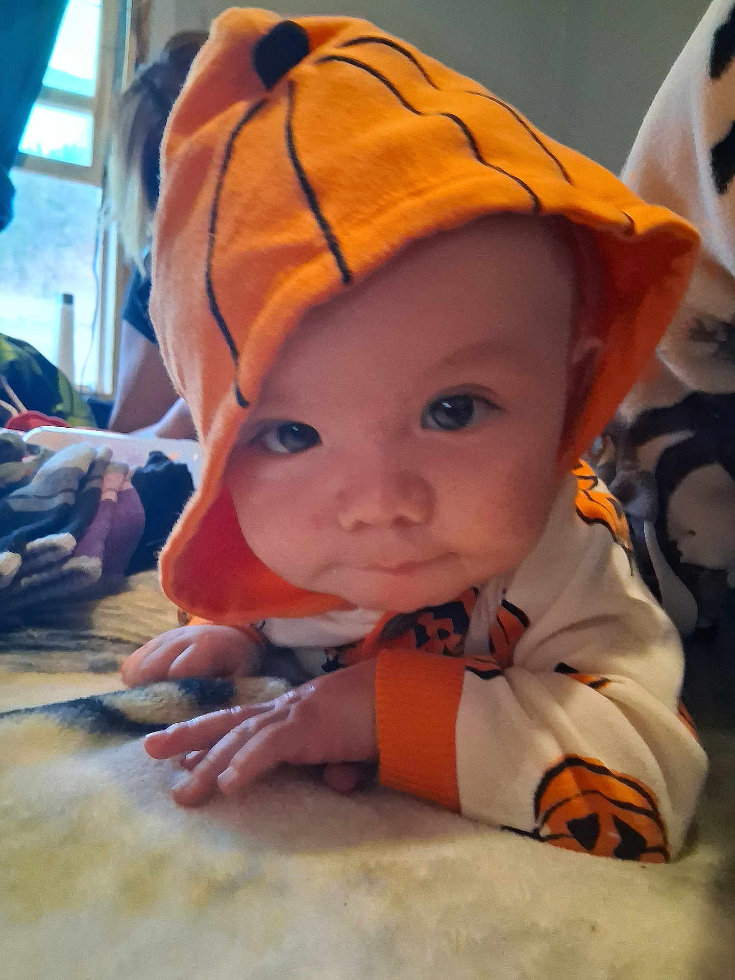 Joseph joined the competition — help win amazing prizes! baby, infant, child, hoodie, orange, pumpkin, blanket, face, eyes, hand, indoor, soft, cute, apparel, costume, portrait, lying_down, person, cozy, curious