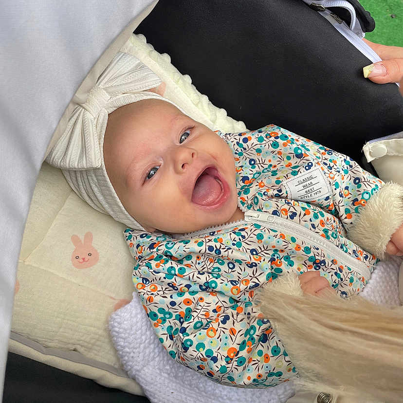 Giulia a rejoint le concours — aidez-le/la à gagner de superbes lots ! baby, babywear, blanket, bow, child, clothing, cute, face, floral_pattern, happy, headband, infant, jacket, outdoor, person, portrait, small, smiling, stroller, warm