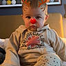 Liam is registered to the contest to win money with this photo: toddler, child, face, reindeer_filter, red_nose, antlers, clothing, sitting, indoors, bed, blanket, painting, wall_art, expression, cute, filter, digital_art, foot, casual_wear, portrait