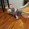 toddler, child, smiling, indoor, wooden_floor, bowl, playful, person, furniture, stool, casual_clothing, socks, hand, adult_arm, toy, carpet, home, happy, flooring, cozy