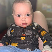 Kayden is registered to the contest to win money with this photo: baby, child, face, eyes, space_theme, clothing, long_sleeve, pants, indoor, portrait, cute, toddler, person, sitting, expression, young_child, infant, looking_at_camera, skin, hand