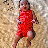 Noah joined the competition — help win amazing prizes! baby, infant, smiling, red_romper, knitted_blanket, milestone_card, 4_months, happy, lying_down, cute, child, portrait, indoors, hand, foot, face, expression, newborn, crawling_age, person