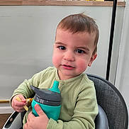 Issac joined the competition — help win amazing prizes! toddler, child, sippy_cup, high_chair, indoor, kitchen, jars, gloves, green_sweater, curly_hair, cute, rosy_cheeks, person, seated, holding, food, snack, expression, face, young_child